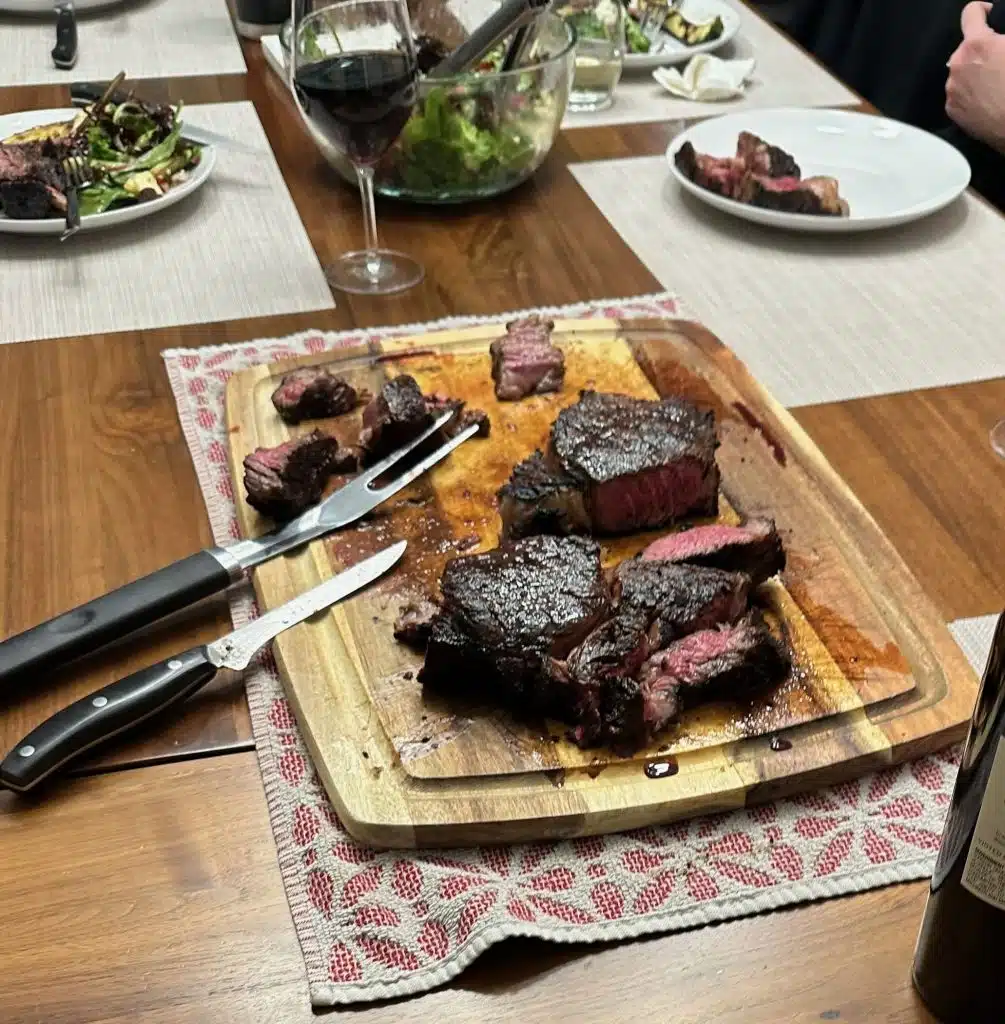 Sweet Heat Rib Eye steak on a wooden platter at a dinner table