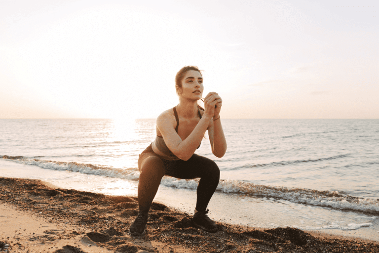 woman doing squats at the beach