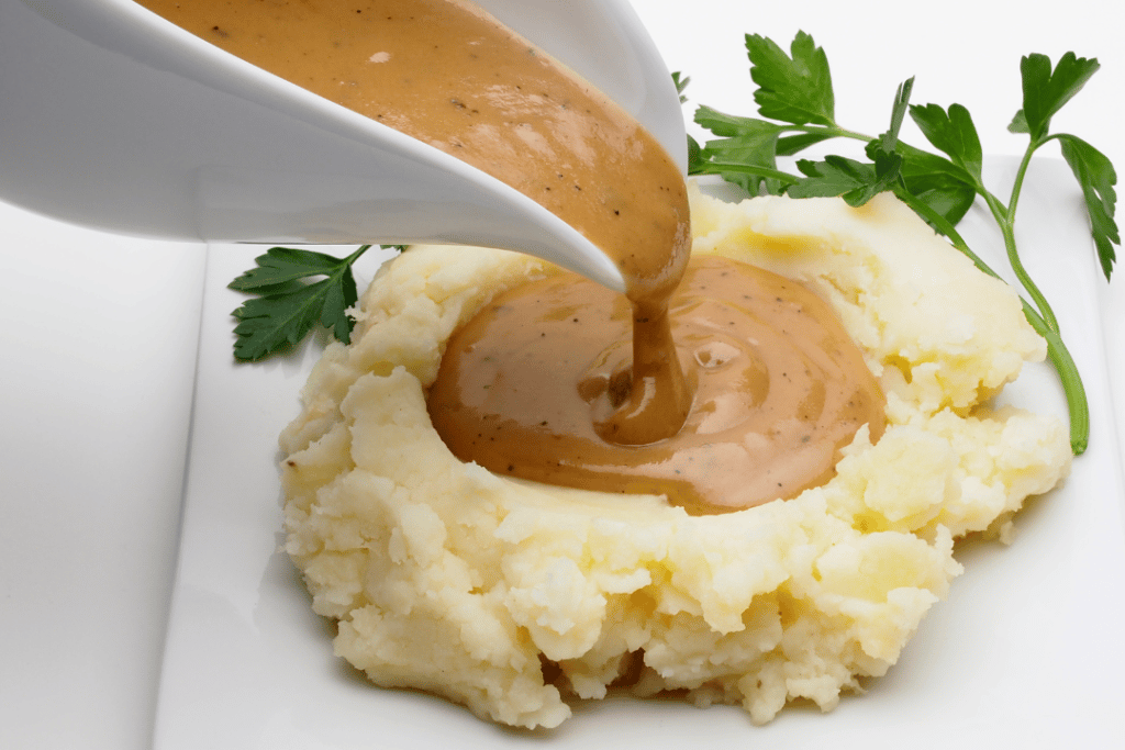 gravy boat pouring rich turkey gravy over mashed potatoes