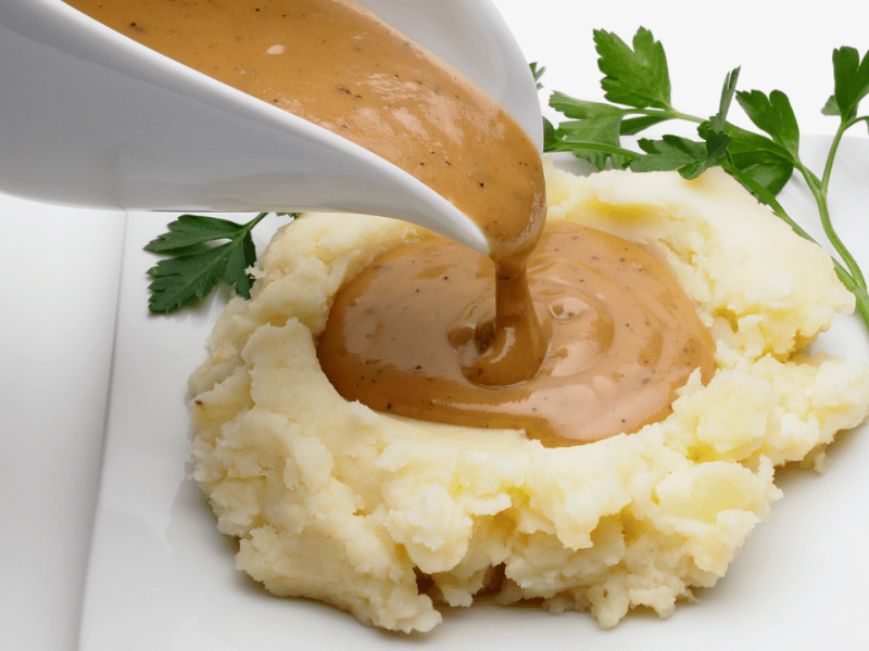 gravy boat pouring rich turkey gravy over mashed potatoes